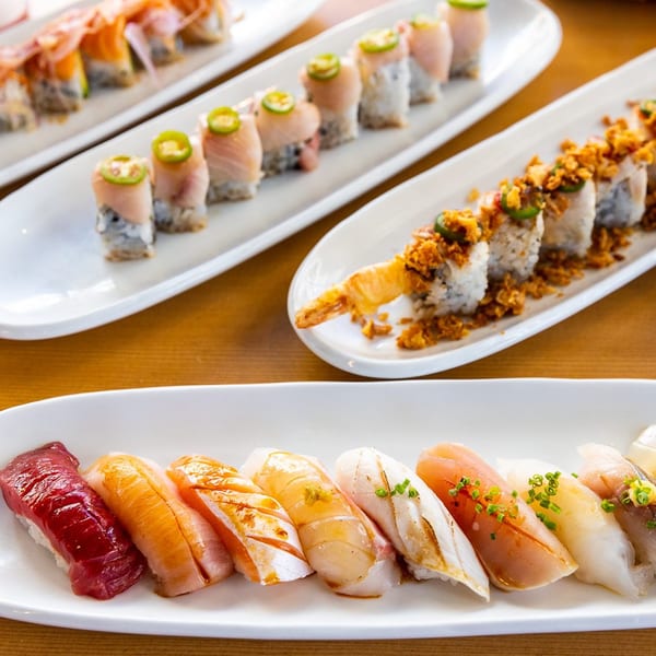 Four plates of various sushi rolls and nigiri, including tuna, salmon, and shrimp tempura rolls.