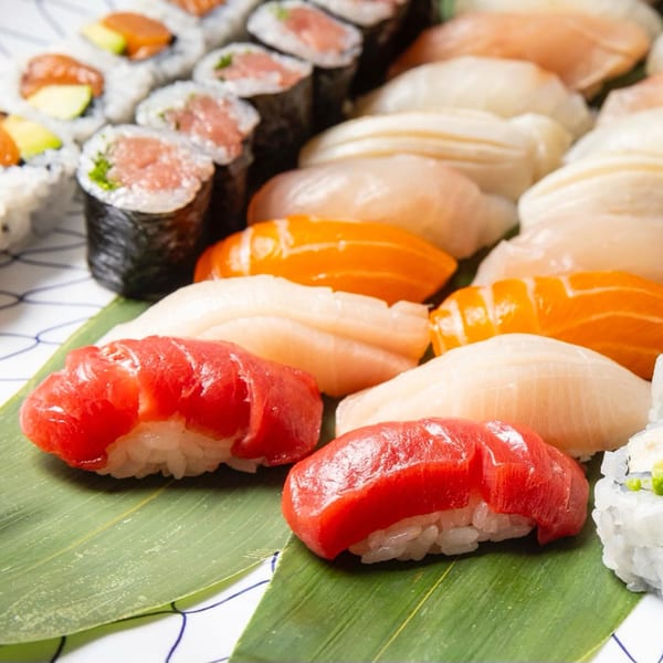 Assorted Kombu Sushi nigiri and maki rolls with tuna, salmon, and white fish on a banana leaf.